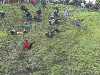 Un grupo de más de diez personas compite bajando una ladera en busca de conseguir un queso Gloucester