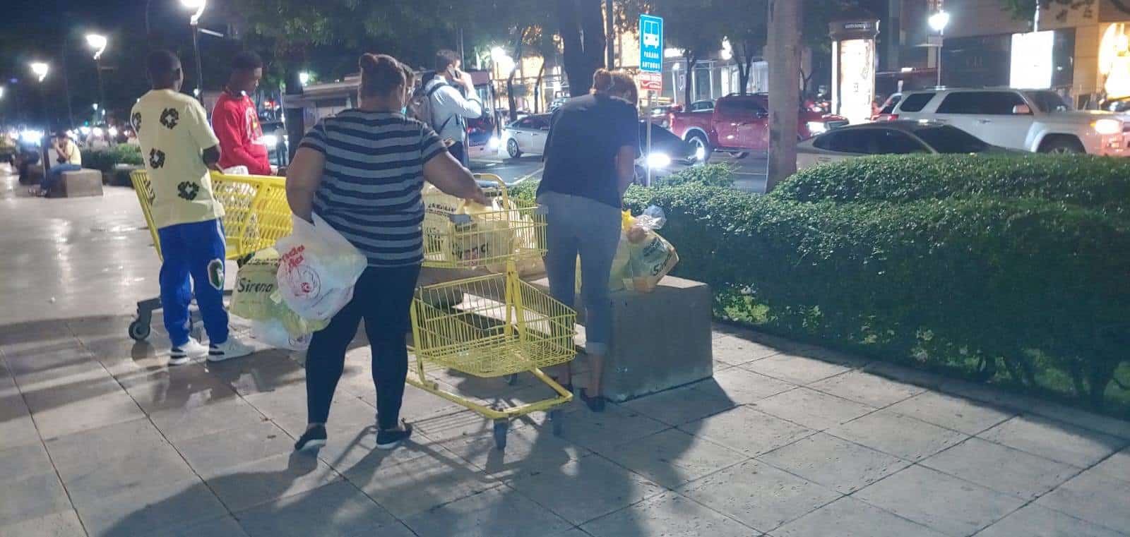 Una familia en espera de un taxi para llegar a su hogar con sus compras.