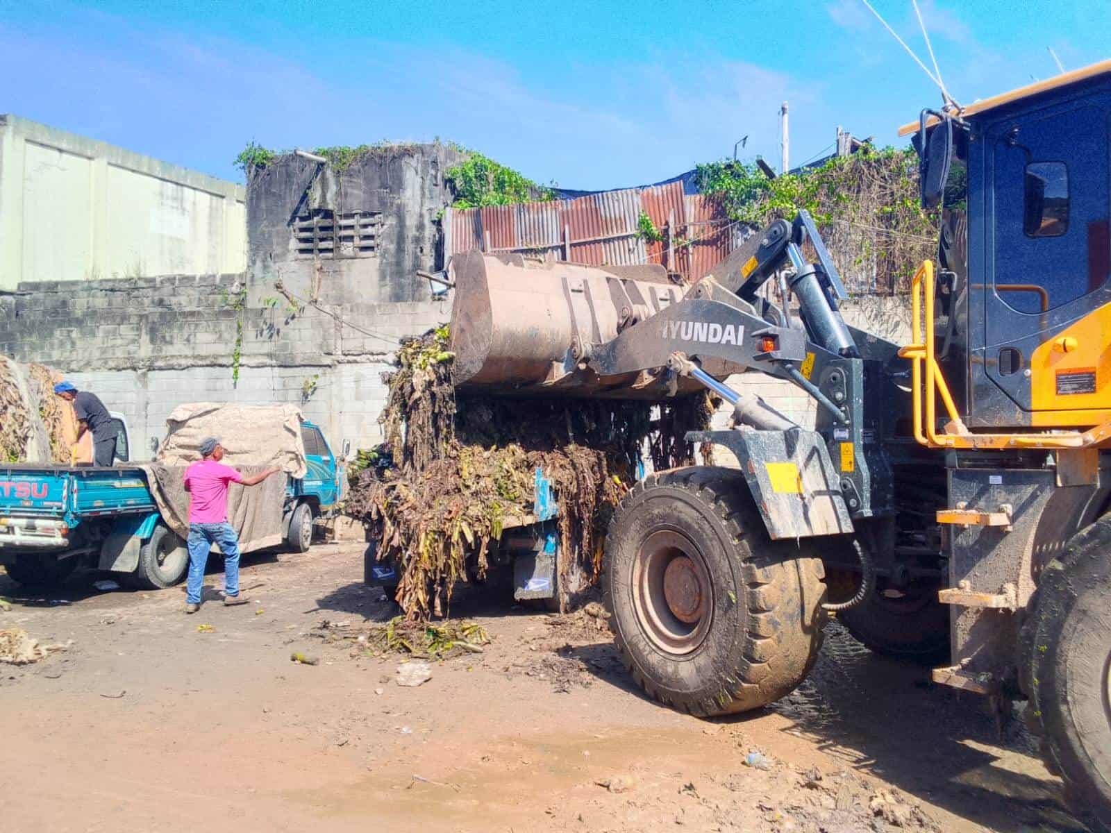 Una retropala recoge la basura en el mercado de Villas Agrícolas.