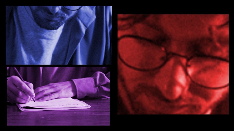 A man with glasses is writing in a notebook, sitting at a table with a serious face. Stylish home interior 