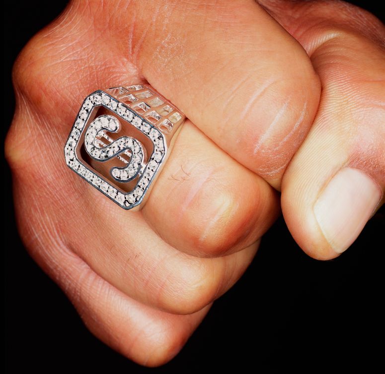 Hombre apretando el puño, anillo con el signo "dólar" en el dedo, primer plano.