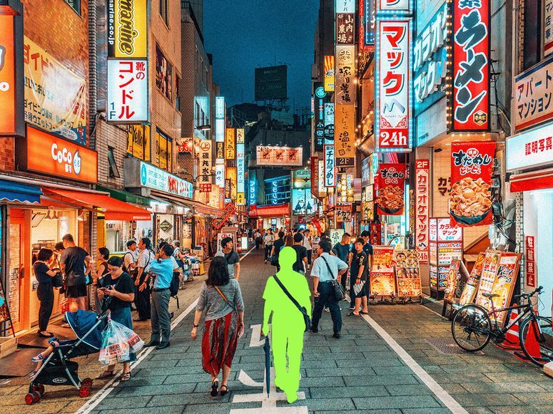 Ilustración fotográfica de personas paseando por el distrito de Shinjuku, en Tokio, Japón. Una de las personas lleva una capa verde que indica que es IA.