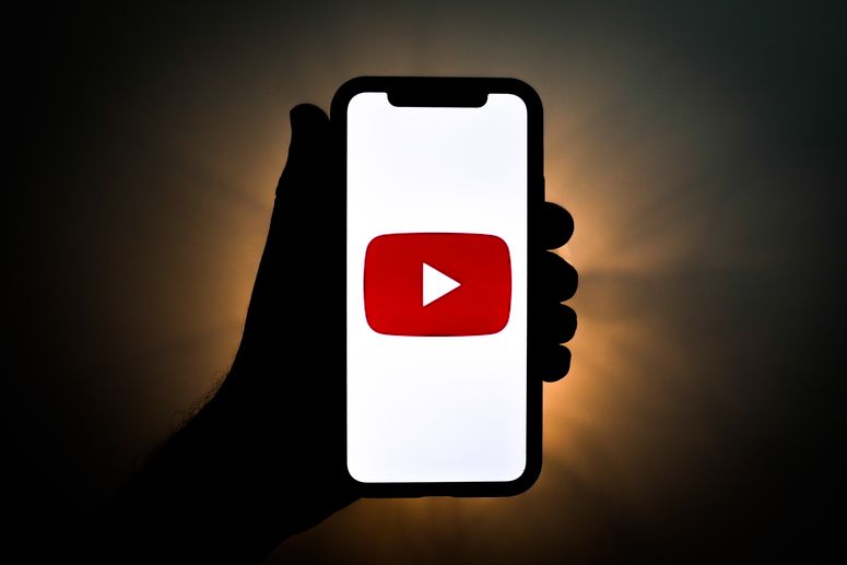 Persona sosteniendo un celular con la pantalla en YouTube. 